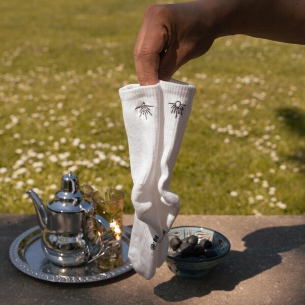 Synix LunaSol sustainable socks in white with sun and moon embroidery held outdoors